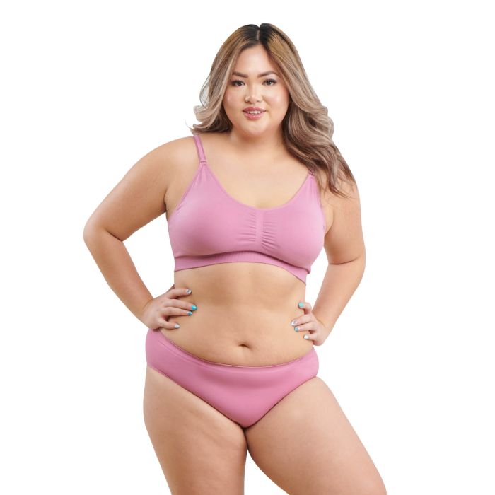 Plus-size model wearing a soft pink wireless bra and matching brief, standing confidently