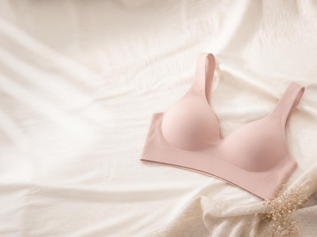 Blush seamless comfort bra on warm ivory linen with open space for headline copy